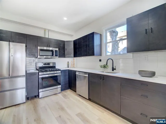 a kitchen with stainless steel appliances a sink a stove a refrigerator and cabinets