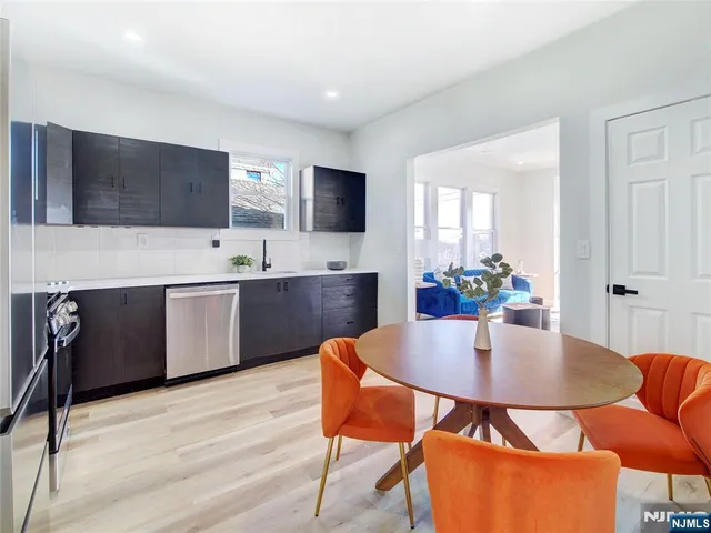 a kitchen with stainless steel appliances kitchen island granite countertop a dining table chairs and a refrigerator