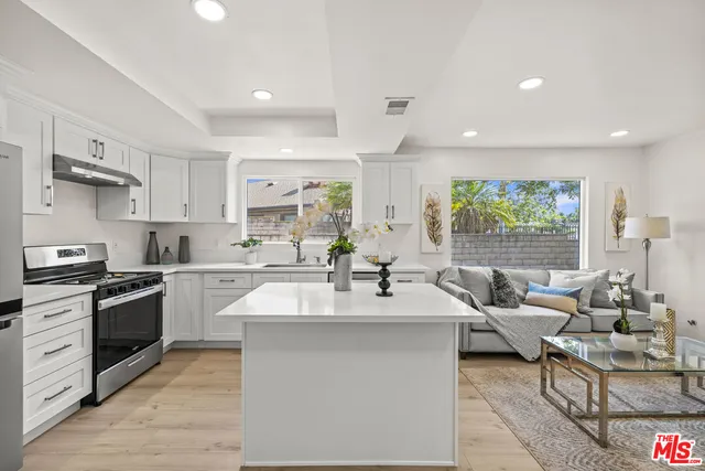 a large kitchen with stainless steel appliances kitchen island granite countertop a sink and a stove