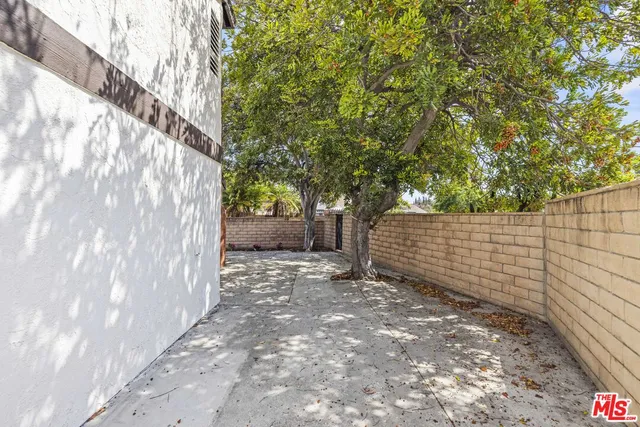 a view of backyard with large trees and wooden fence