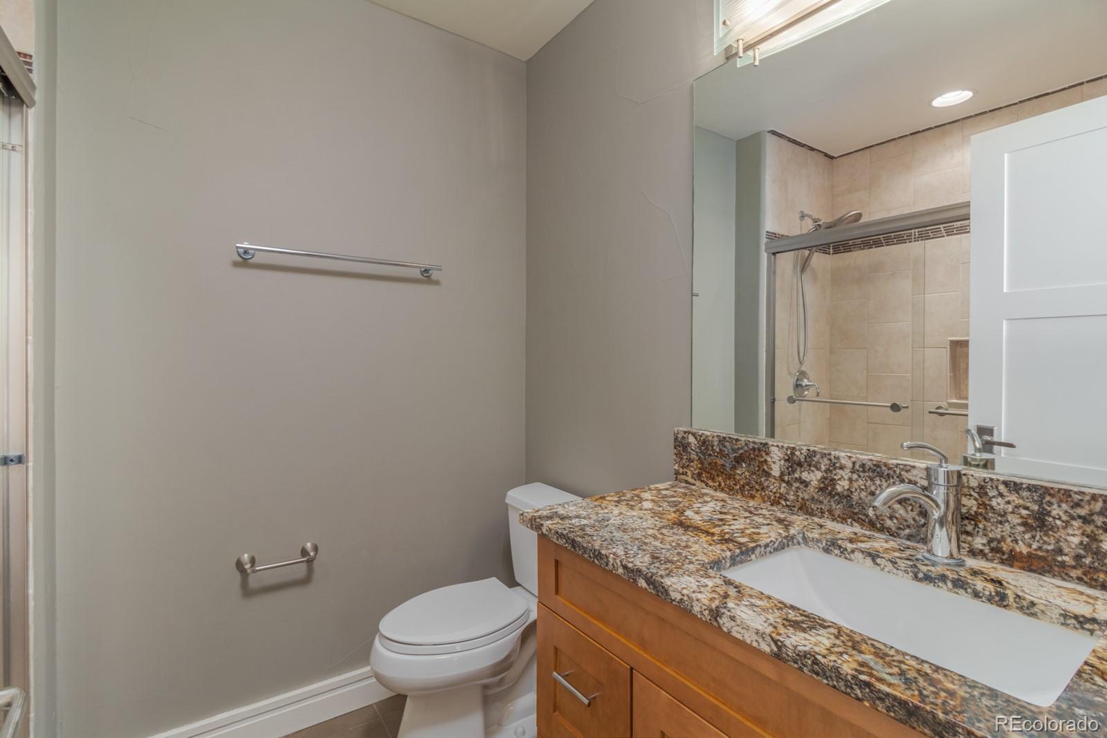 5241 Raintree Circle Parker, CO 80134 - Photo 27 of 36 a bathroom with a granite countertop sink a toilet and a mirror