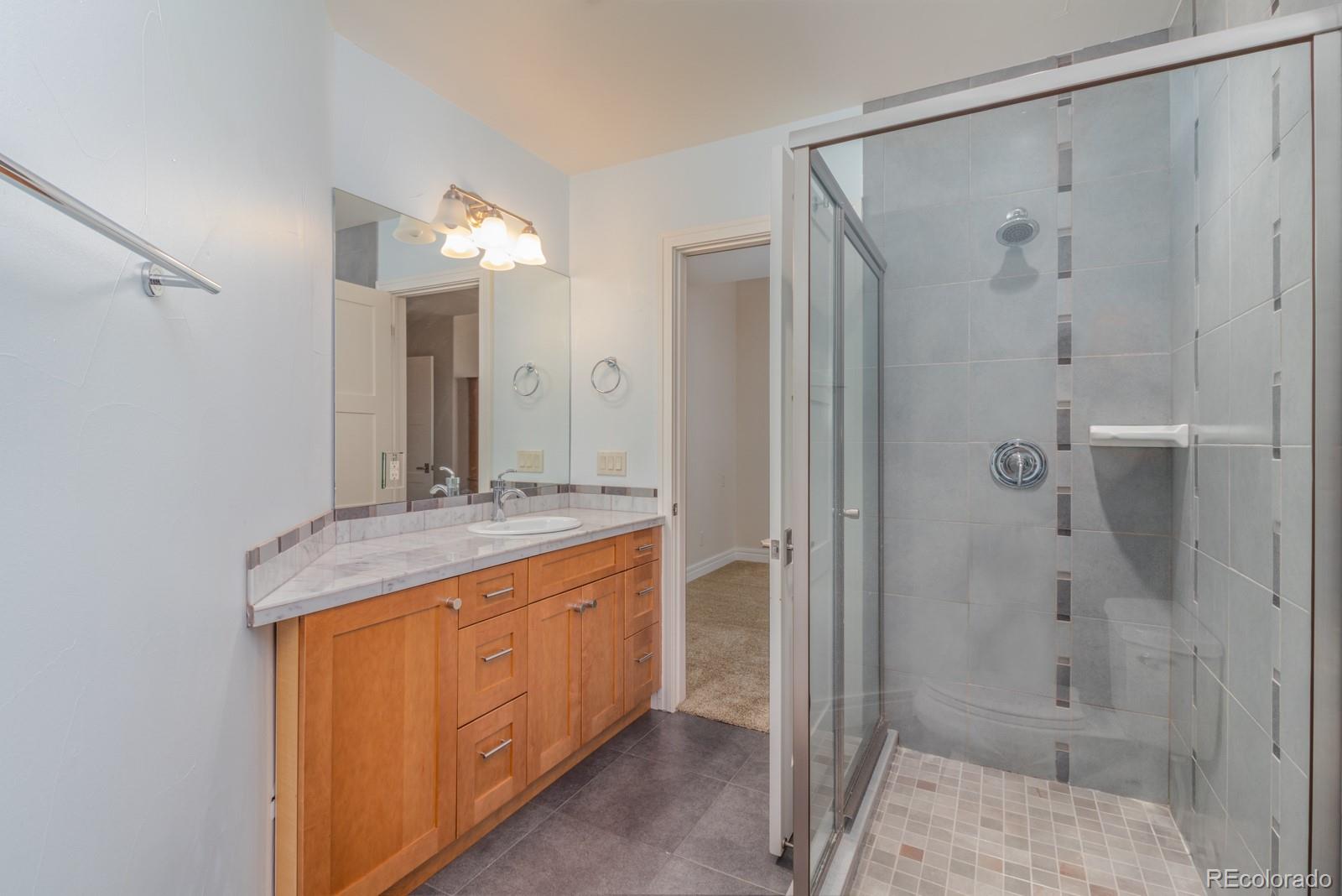 5241 Raintree Circle Parker, CO 80134 - Photo 29 of 36 a bathroom with a granite countertop sink mirror and shower