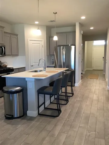 a dining hall with stainless steel appliances granite countertop a stove a sink dishwasher and a refrigerator with wooden floor