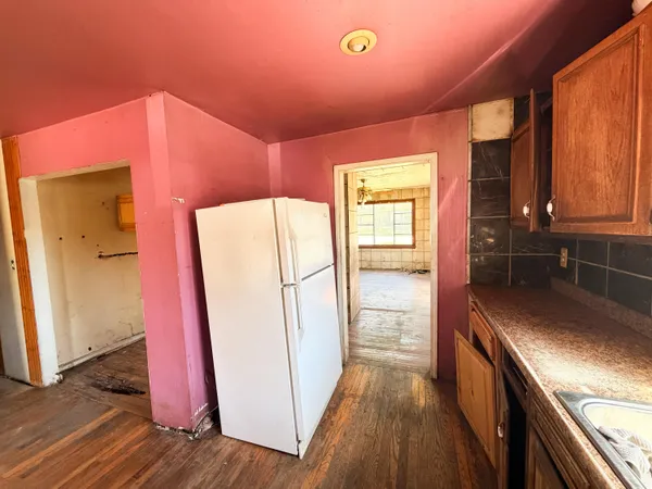 a kitchen with sink a refrigerator and wooden floor