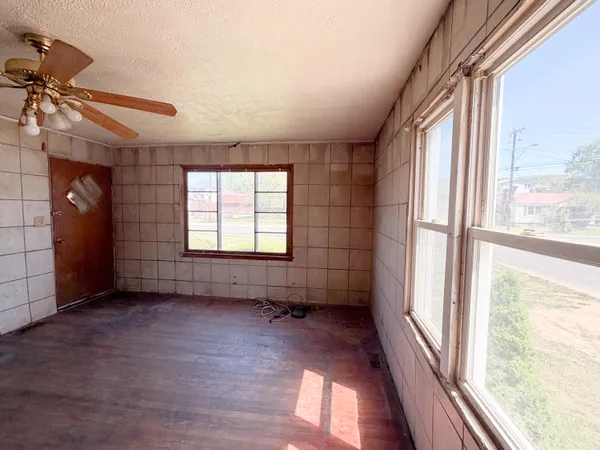 a view of empty room with wooden floor and fan
