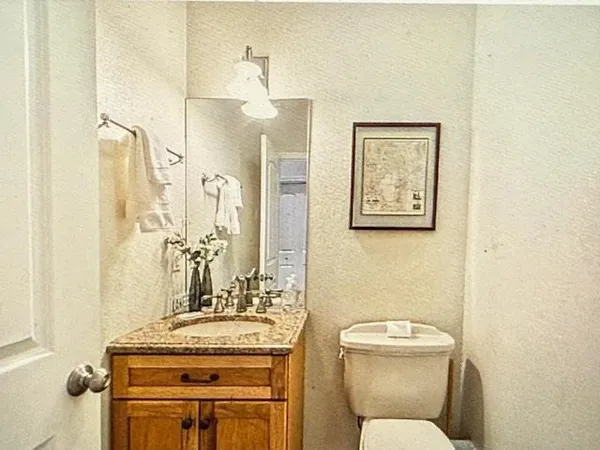a bathroom with a granite countertop toilet sink and mirror
