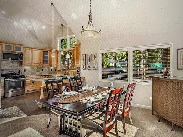 a dining room with wooden floor a chandelier a wooden table and chairs