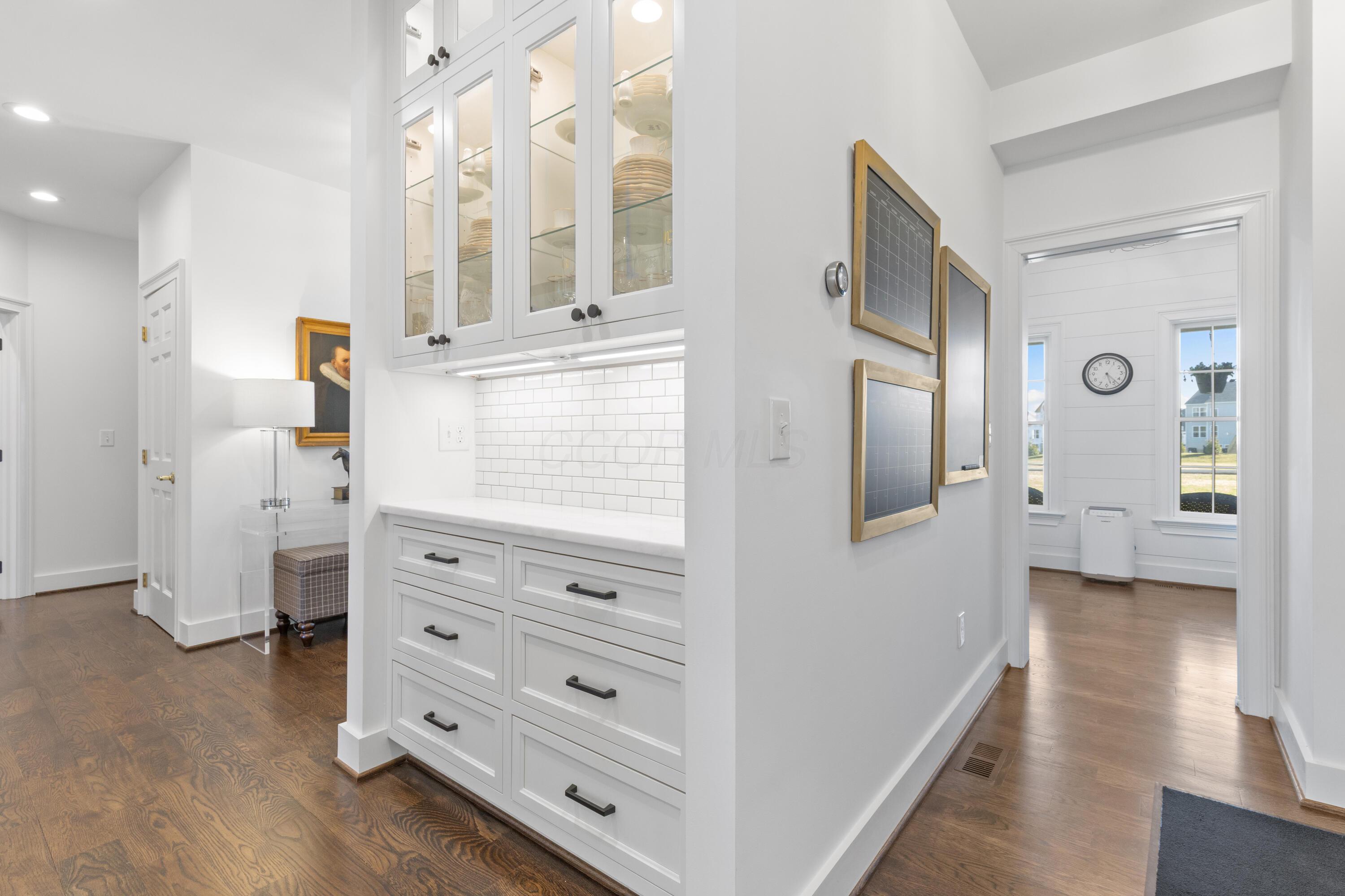 1364 Dale Ford Road Delaware, OH 43015 - Photo 15 of 112 • Hardwood flooring • White painted walls • Custom built wall cabinets • Custom built beverage center • Marble countertop • Ceramic tile backsplash • Soft-close drawers • Under cabinet lighting • Custom built china cabinet