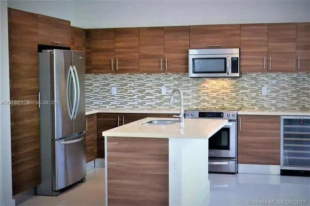 a kitchen with stainless steel appliances kitchen island a sink stove and refrigerator