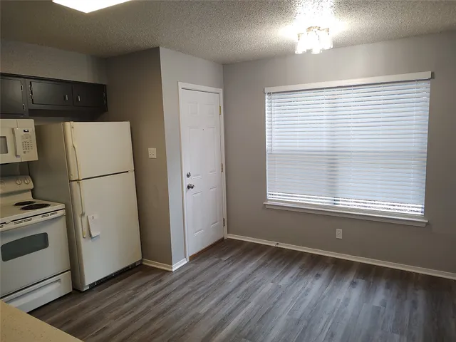 a view of a kitchen with a fridge wooden floor and a window
