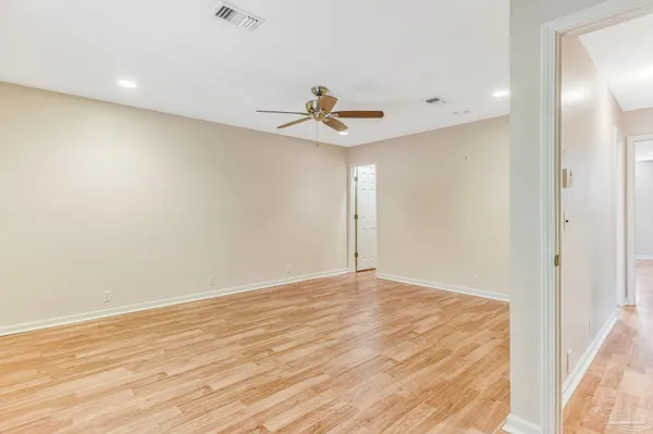 an empty room with wooden floor closet and fan