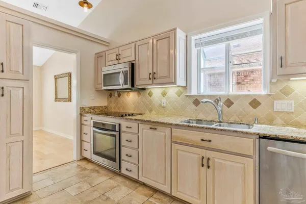 a kitchen with granite countertop white cabinets stainless steel appliances a sink and a window