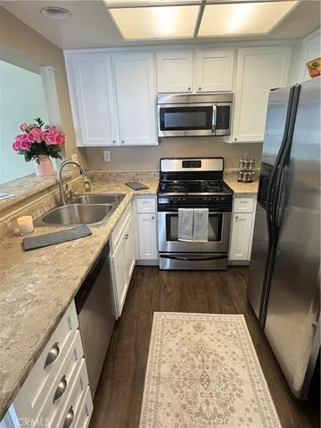 a kitchen with granite countertop a sink stainless steel appliances and cabinets