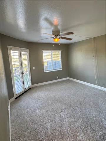 an empty room with windows and chandelier fan