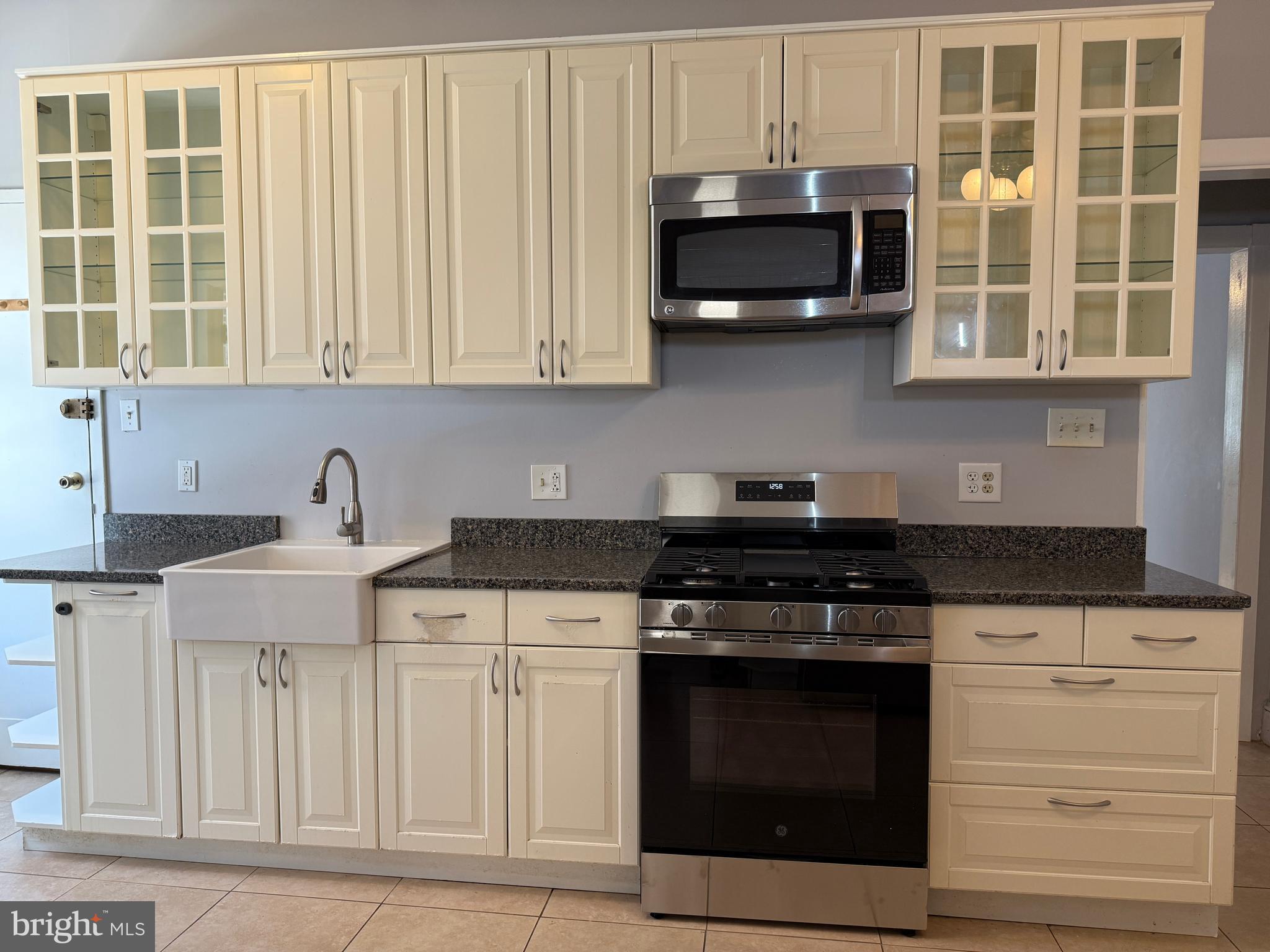 a kitchen with stainless steel appliances granite countertop white cabinets and a stove top oven