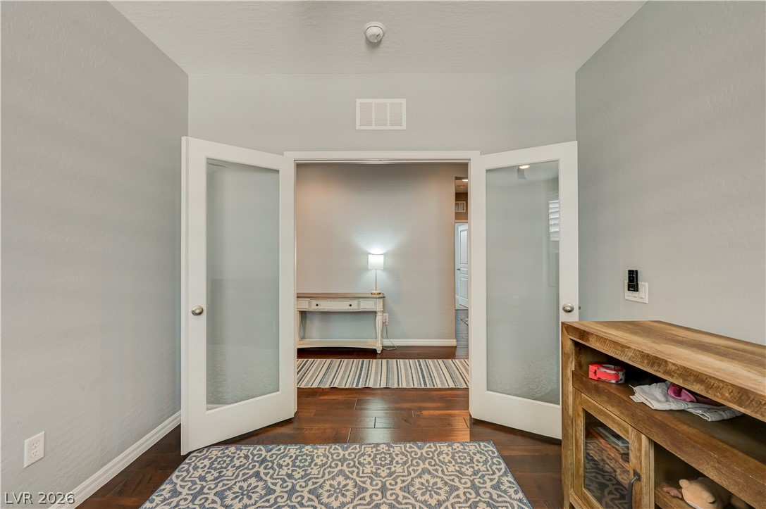7049 Motley Road Las Vegas, NV 89178 - Photo 15 of 61 Double glass doors open to reveal rich wood flooring and a versatile hallway transition.