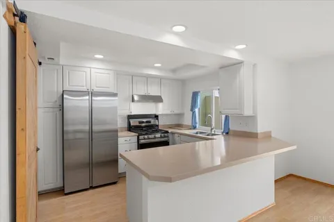 a kitchen with stainless steel appliances granite countertop a refrigerator a sink a stove a microwave and island