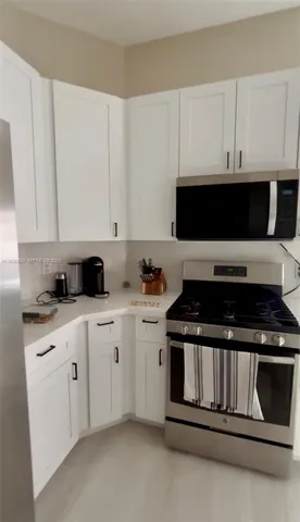a kitchen with granite countertop white cabinets and black stove top oven