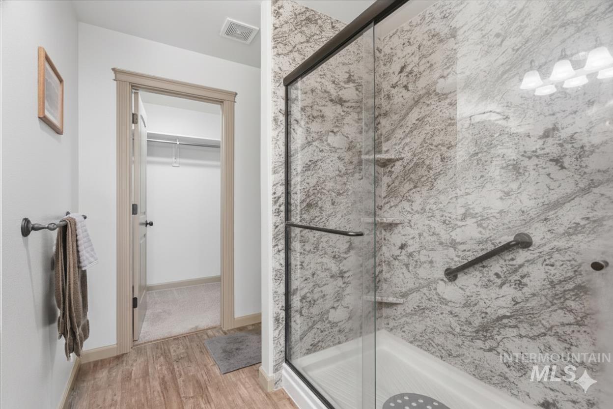 679 North Shadowfox Place Eagle, ID 83616 - Photo 7 of 28 Full bathroom featuring a marble finish shower, a walk in closet, and light wood-style floors