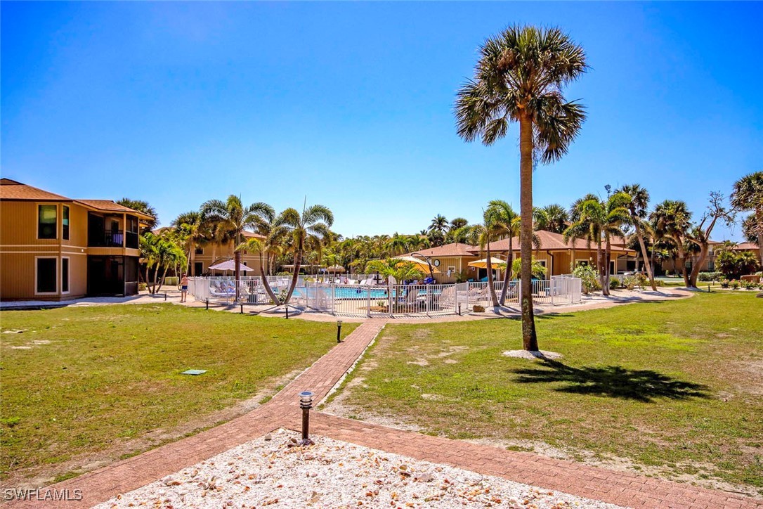 5117 Sea Bell Road, Unit B101 Sanibel, FL 33957 - Photo 2 of 23 a view of a swimming pool with a lawn chairs under palm trees