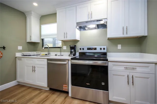 a kitchen with white cabinets and appliances