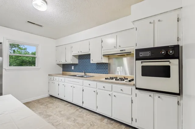 a kitchen with granite countertop white cabinets and white appliances