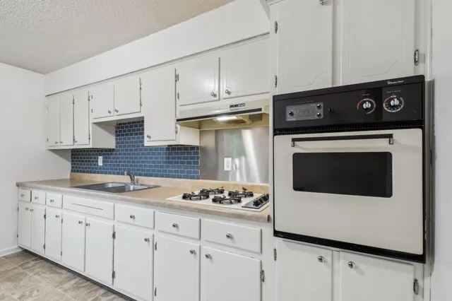 a kitchen with granite countertop white cabinets and white appliances