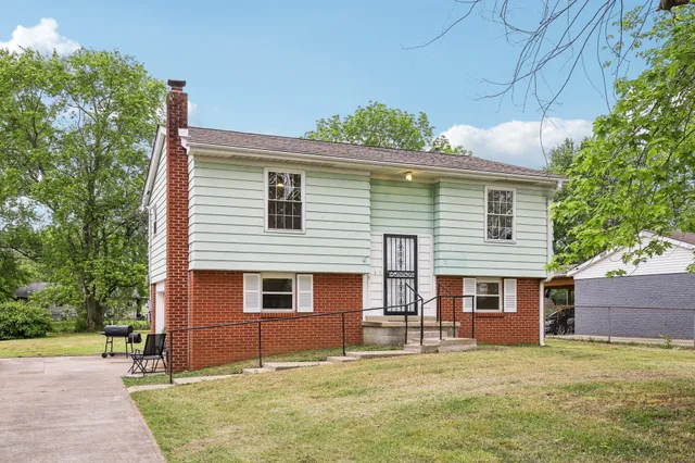 a view of a house with a backyard and a tree