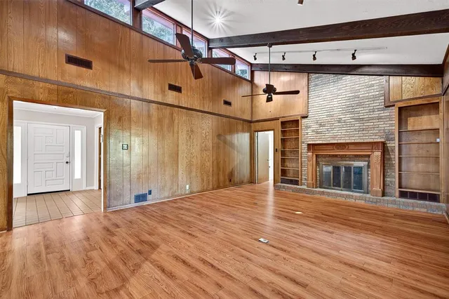 a view of an empty room with wooden floor and a fireplace