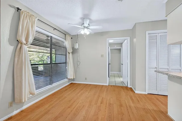 a view of empty room with wooden floor and fan