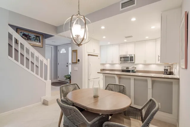 a kitchen with stainless steel appliances kitchen island granite countertop a sink a stove a dining table and chairs