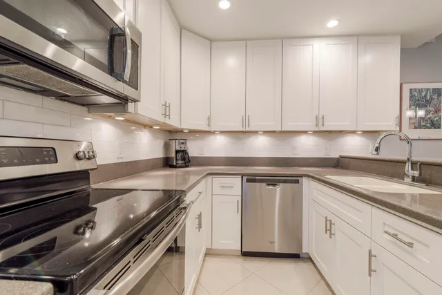 a kitchen with granite countertop a sink stainless steel appliances and cabinets