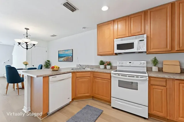 a kitchen with granite countertop white cabinets a stove a sink and a potted plant