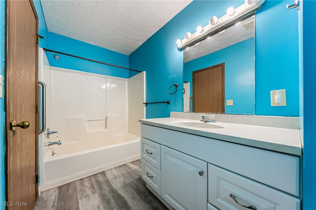 761 Garfield Street Akron, OH 44310 - Photo 18 of 31 Full bathroom with tub / shower combination, vanity, a textured ceiling, and dark wood-type flooring