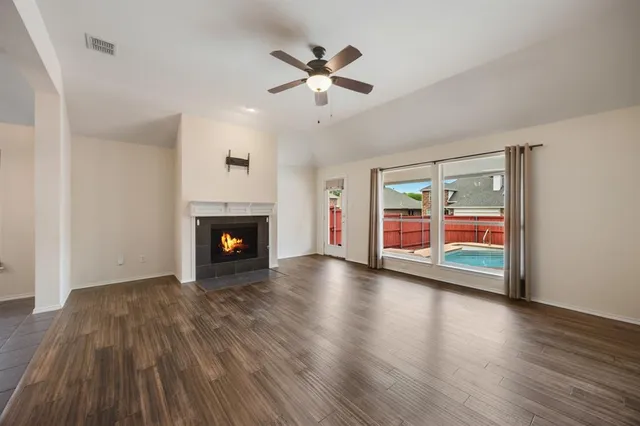 a view of an empty room with wooden floor fireplace and a window