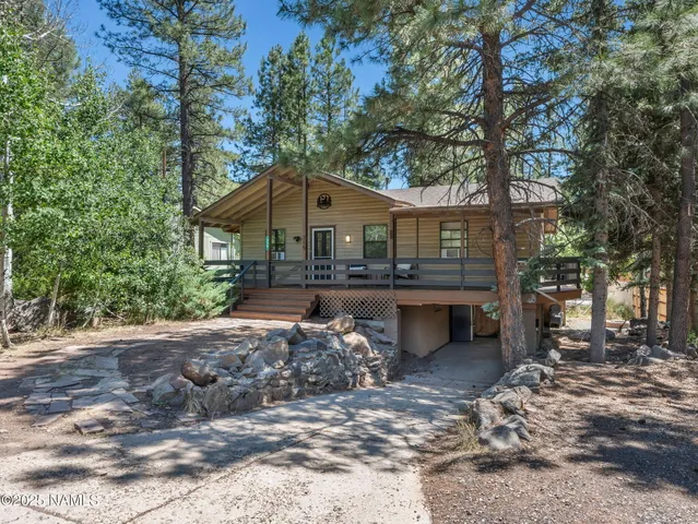 a view of a house with a yard and large tree