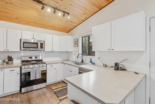 a kitchen with stainless steel appliances a sink a stove top oven a counter space and cabinets