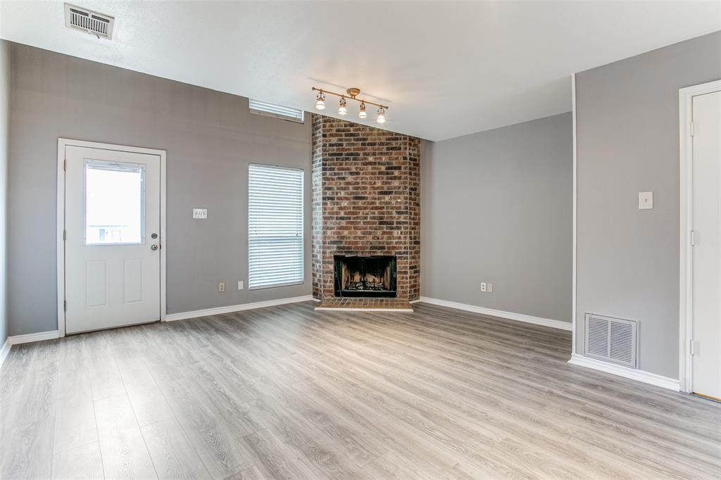 12 Abbey Road Euless, TX 76039 - Photo 2 of 12 living room with light wood finished floors, a brick fireplace, and lofted ceiling