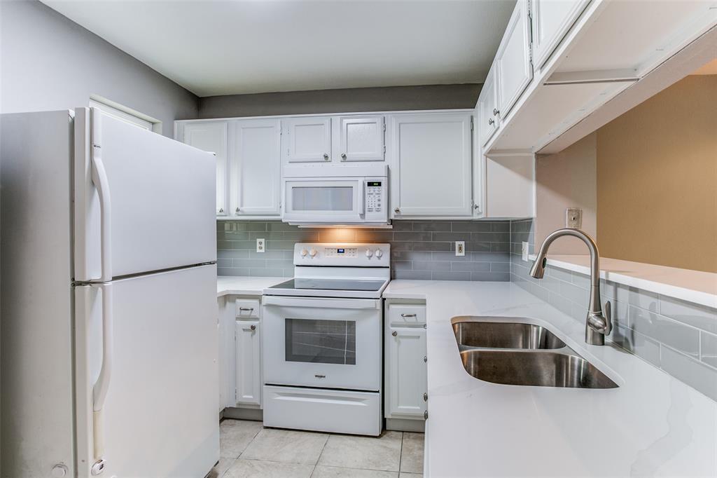 12 Abbey Road Euless, TX 76039 - Photo 7 of 12 Kitchen featuring white appliances, white cabinets, backsplash, and light tile patterned floors