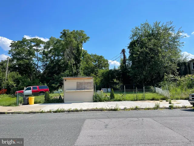 a sign board with flower plants and large trees