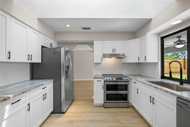 a kitchen with white cabinets and stainless steel appliances