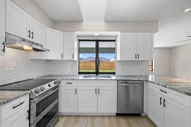 a kitchen with white cabinets appliances and a sink