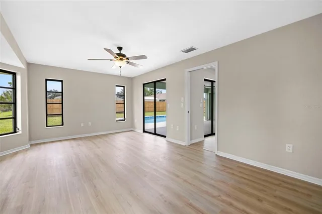 a view of an empty room with window and wooden floor