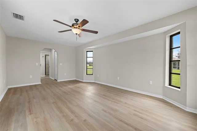 a view of an empty room with window and wooden floor