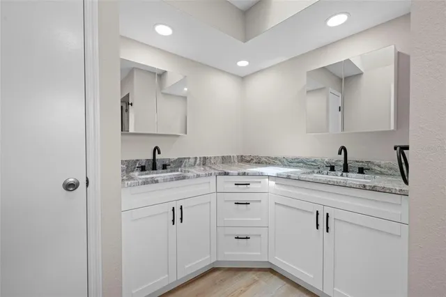 a bathroom with a granite countertop sink mirror and cabinets