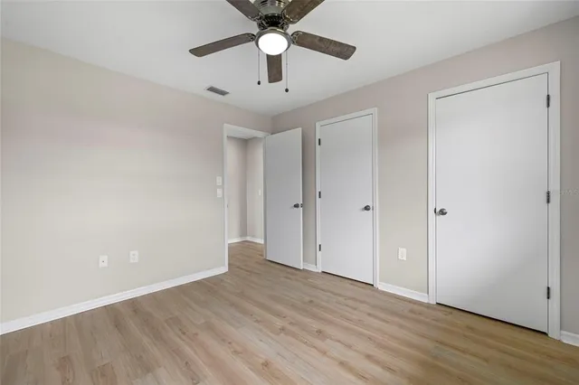 an empty room with wooden floor chandelier fan and closet area