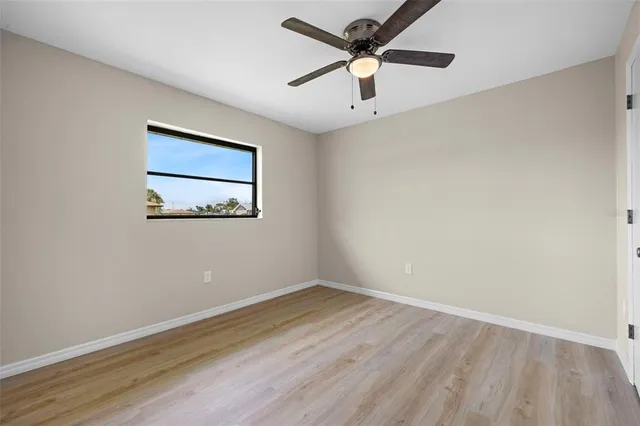 an empty room with a window and a ceiling fan