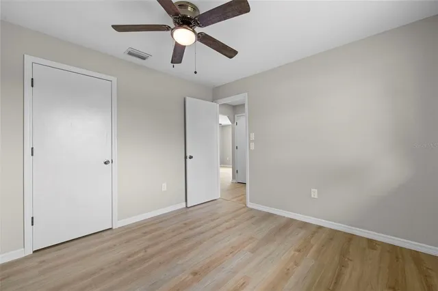 an empty room with wooden floor and ceiling fan