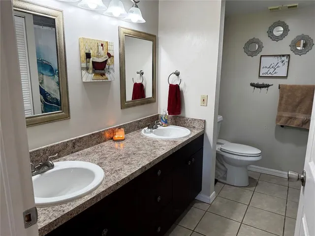 a bathroom with a granite countertop sink a toilet and a mirror