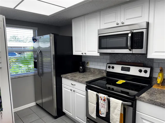 a kitchen with stainless steel appliances granite countertop a stove a refrigerator and a microwave